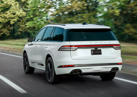 A white 2025 Lincoln Aviator® SUV is being driven away down a road lined with colorful trees. | Astro Lincoln in Pensacola FL