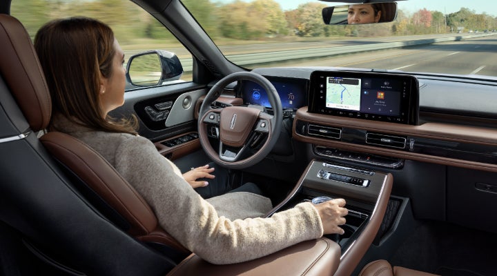A 2026 Lincoln Aviator® SUV is being driven hands-free on a highway near a forest | Astro Lincoln in Pensacola FL
