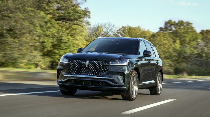 A 2026 Lincoln Black Label™ Aviator® SUV is being driven down a road lined with trees. | Astro Lincoln in Pensacola FL