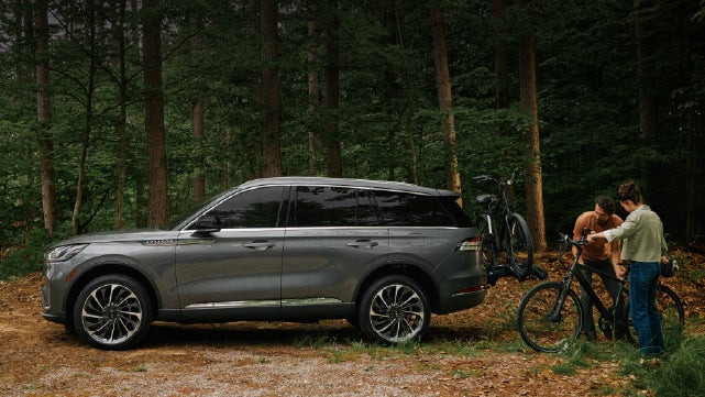 A father and son load e-bikes on a bike rack attached to a 2027 Lincoln Aviator® SUV. | Astro Lincoln in Pensacola FL