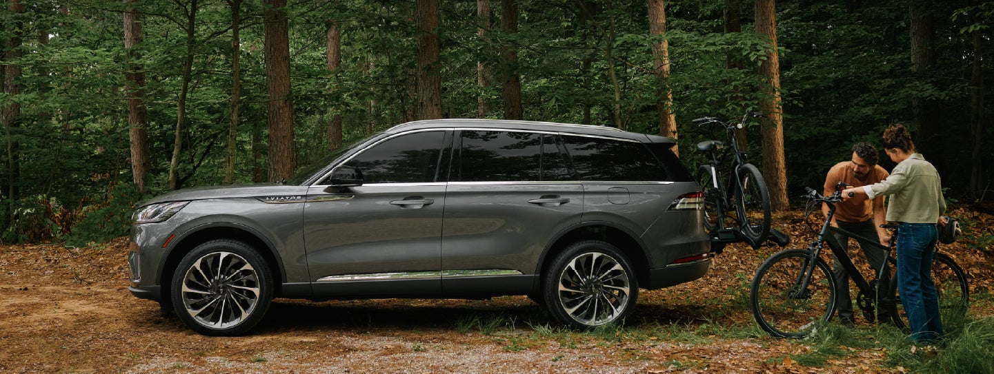 A father and son load e-bikes on a bike rack attached to a 2027 Lincoln Aviator® SUV. | Astro Lincoln in Pensacola FL